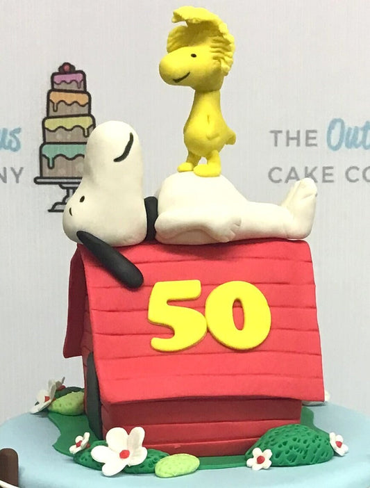 Handmade edible fondant Snoopy and Woodstock lying on kennel